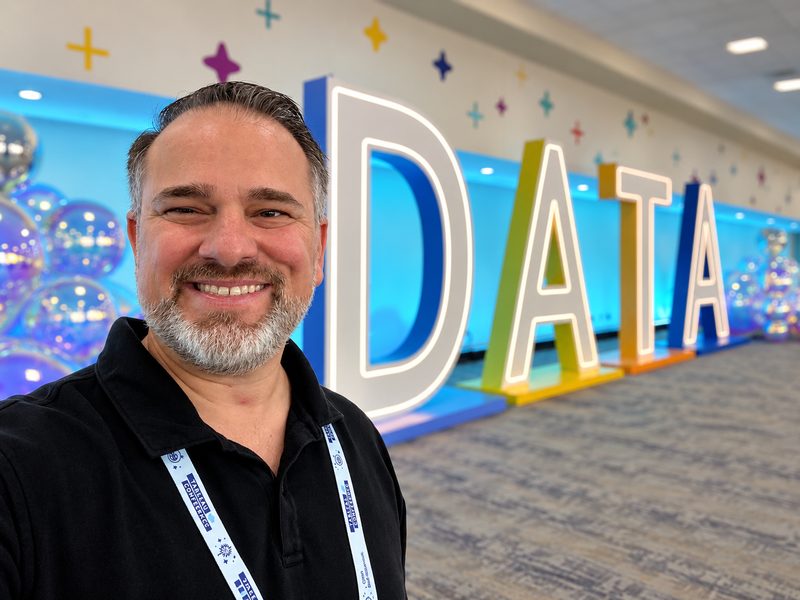 Jeremy Dempsey smiling in front of large illuminated letters spelling DATA at a Tableau conference.